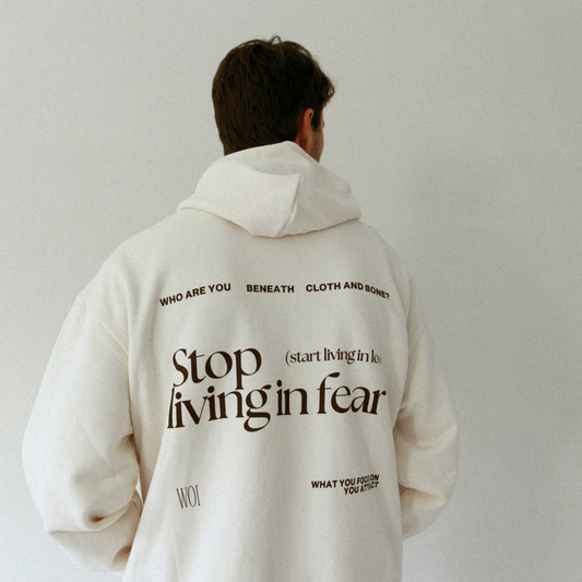 Person wearing a white hoodie with motivational text on the back against a plain background