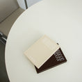 Load image into Gallery viewer, Two books stacked on a round white table