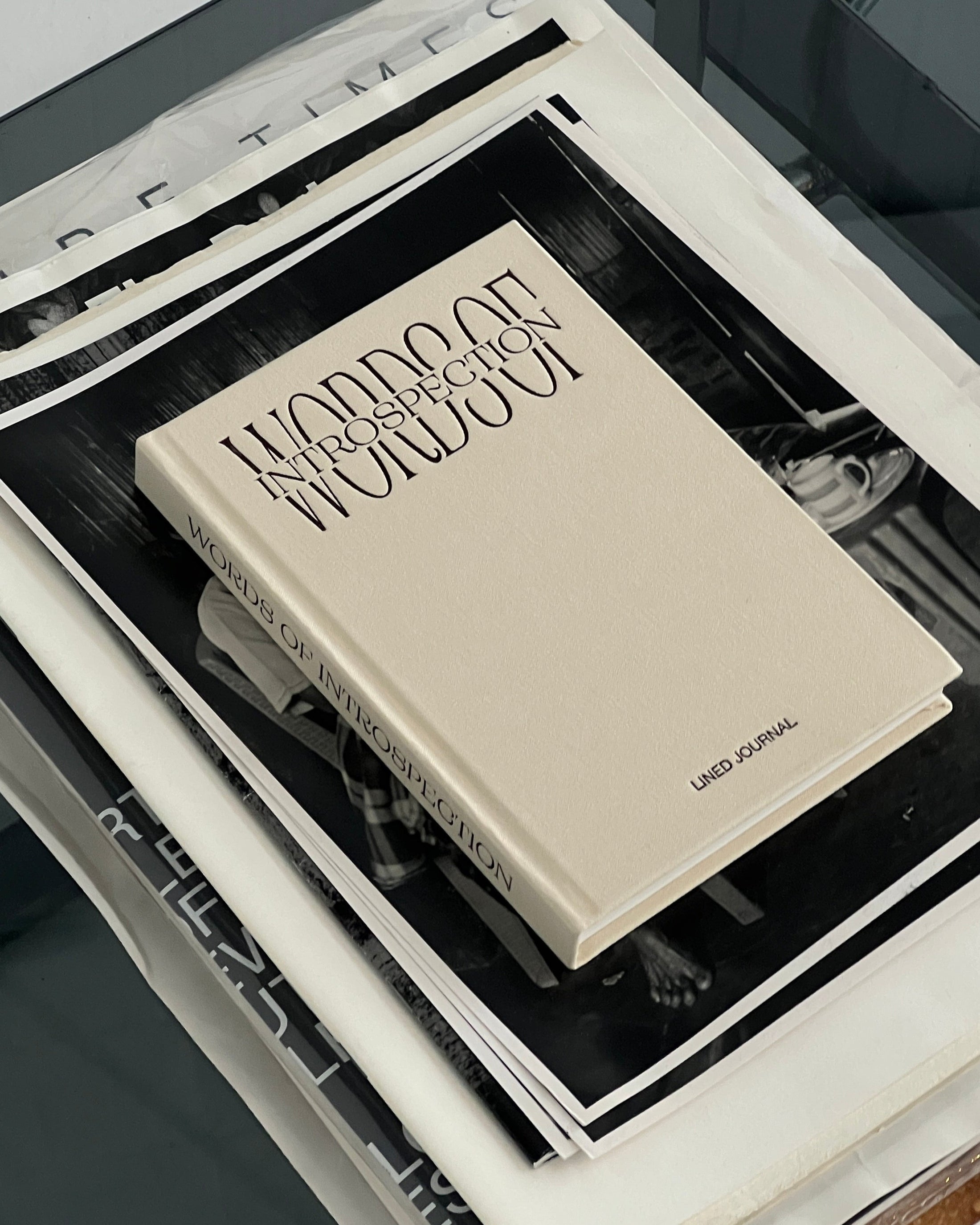 Stack of books with a beige cover titled 'Words Of Introspection, Lined Journal' by WOI.