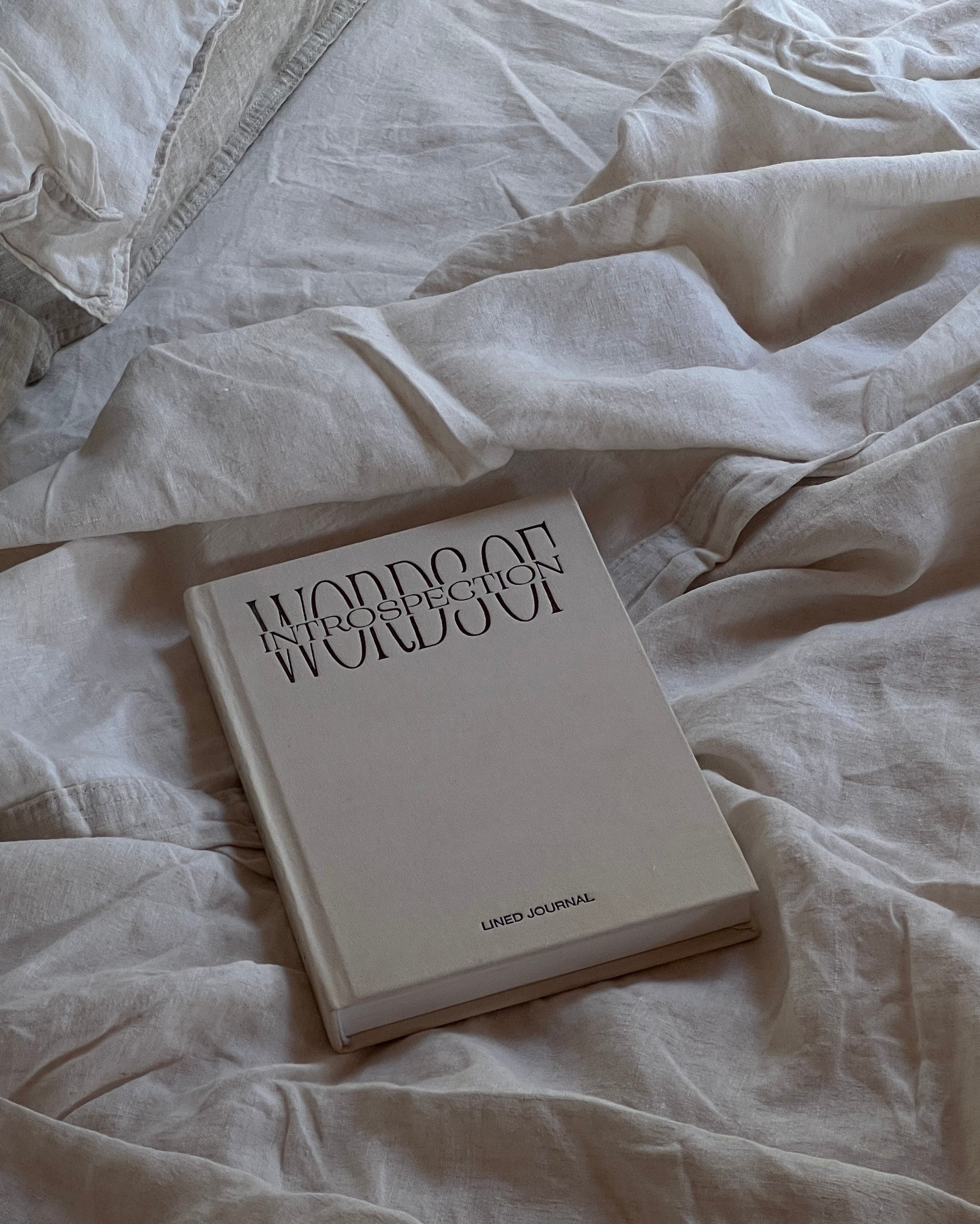 Book titled 'Words of Introspection - lined journal' on a bed