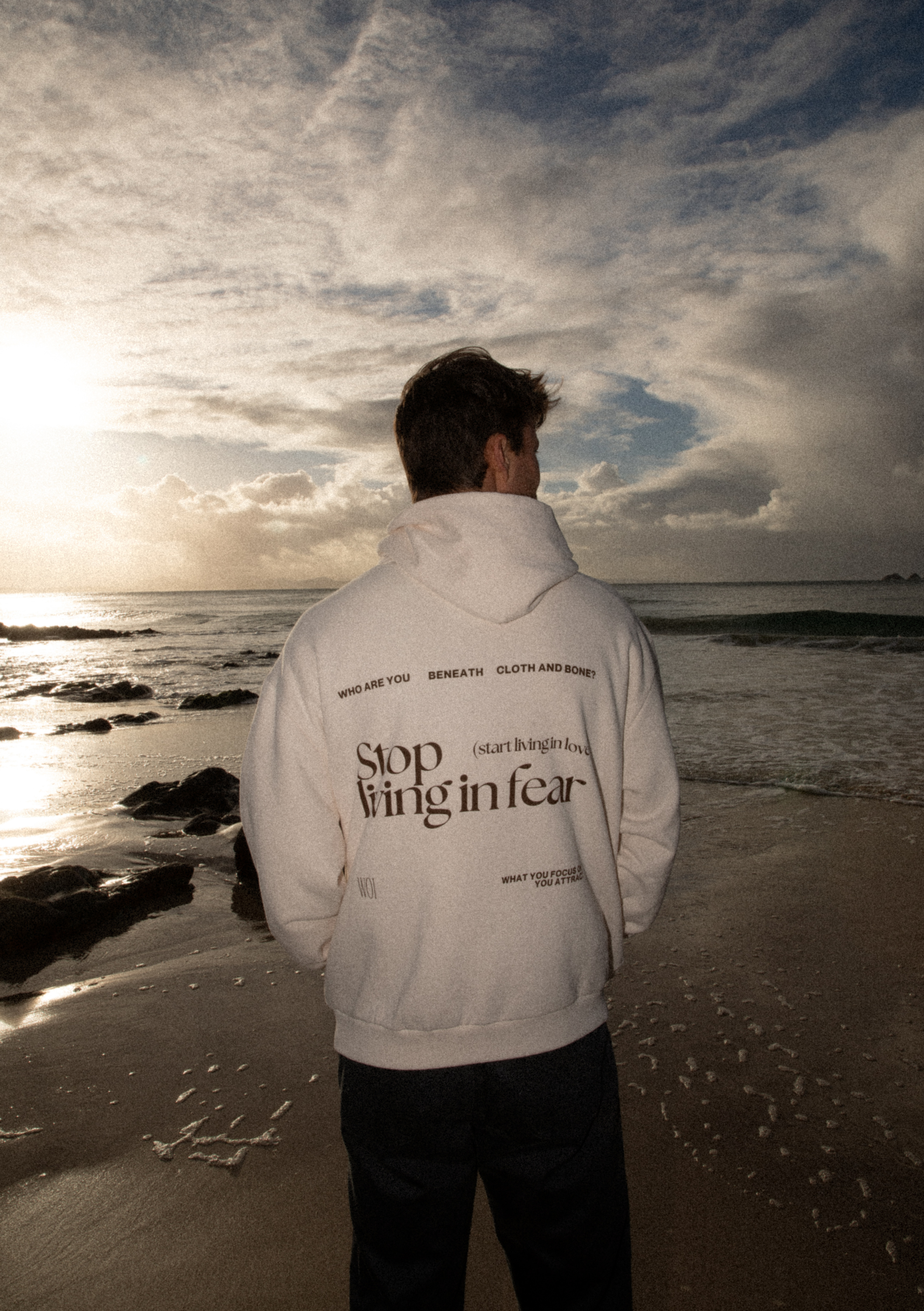 man standing on beach wearing hoodie